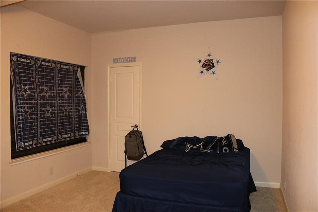 A bedroom with a bed and a backpack on the floor.