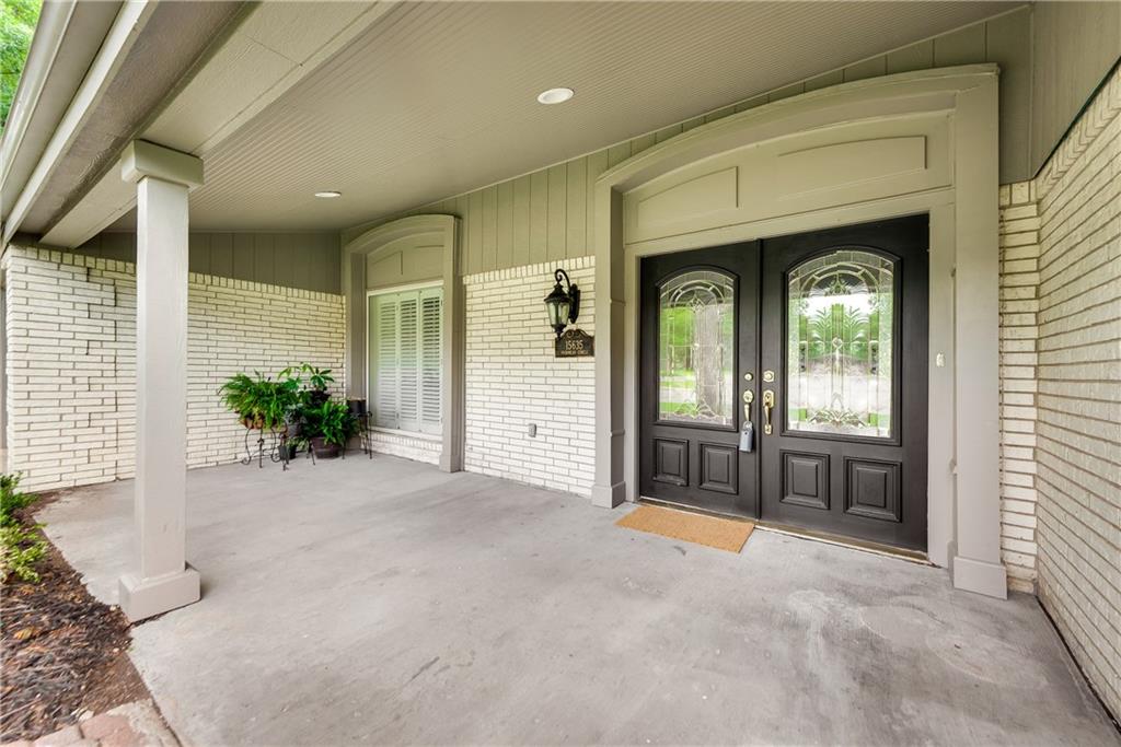 The front door of a house with a covered porch and two black doors.