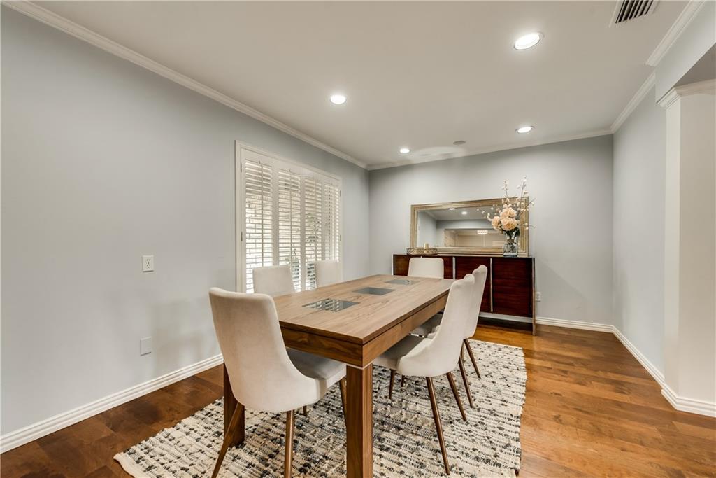 A dining room with a wooden table and chairs and a rug.