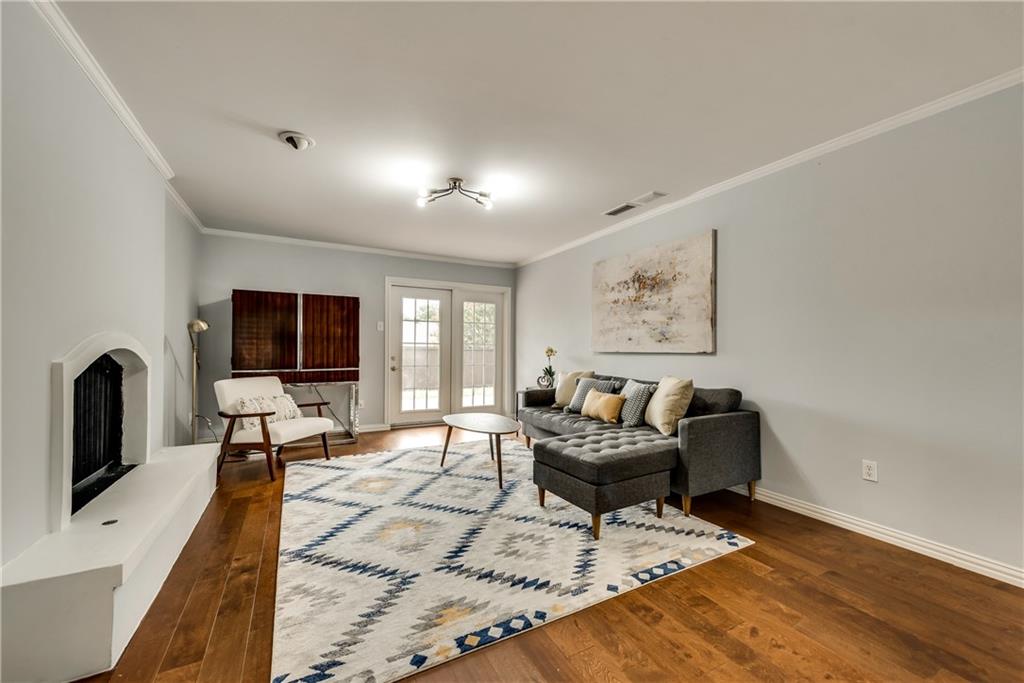 A living room with hardwood floors , a couch , chairs , and a fireplace.