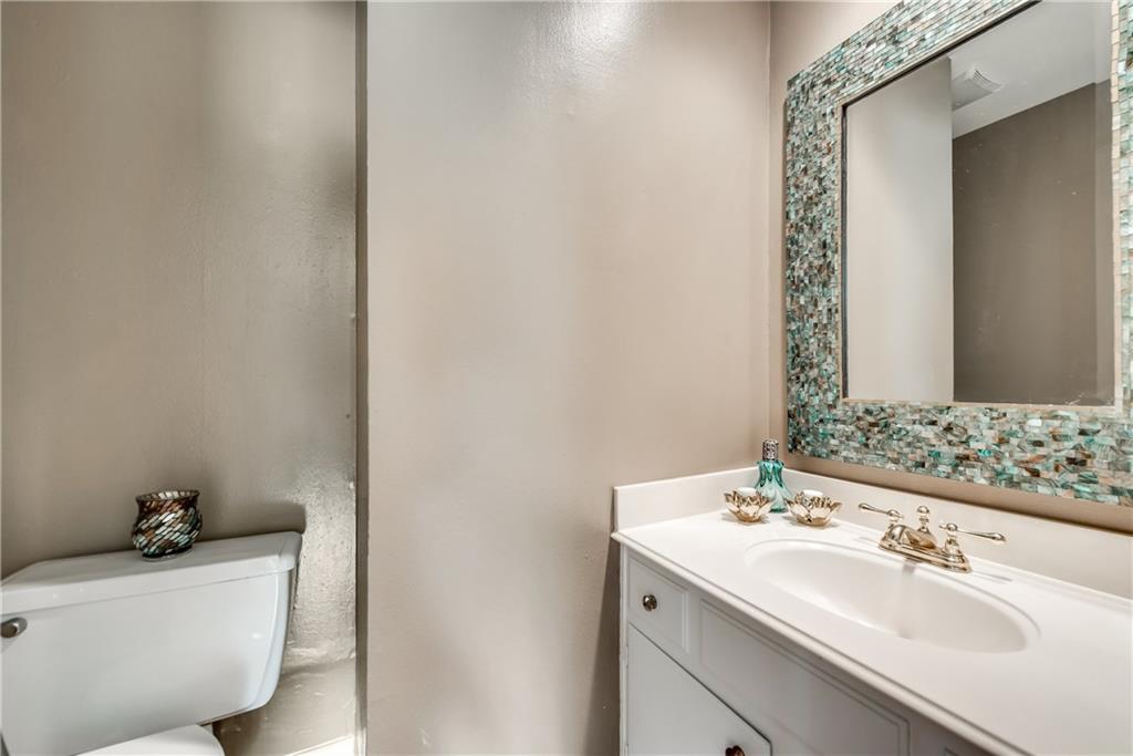 A bathroom with a toilet , sink and mirror.