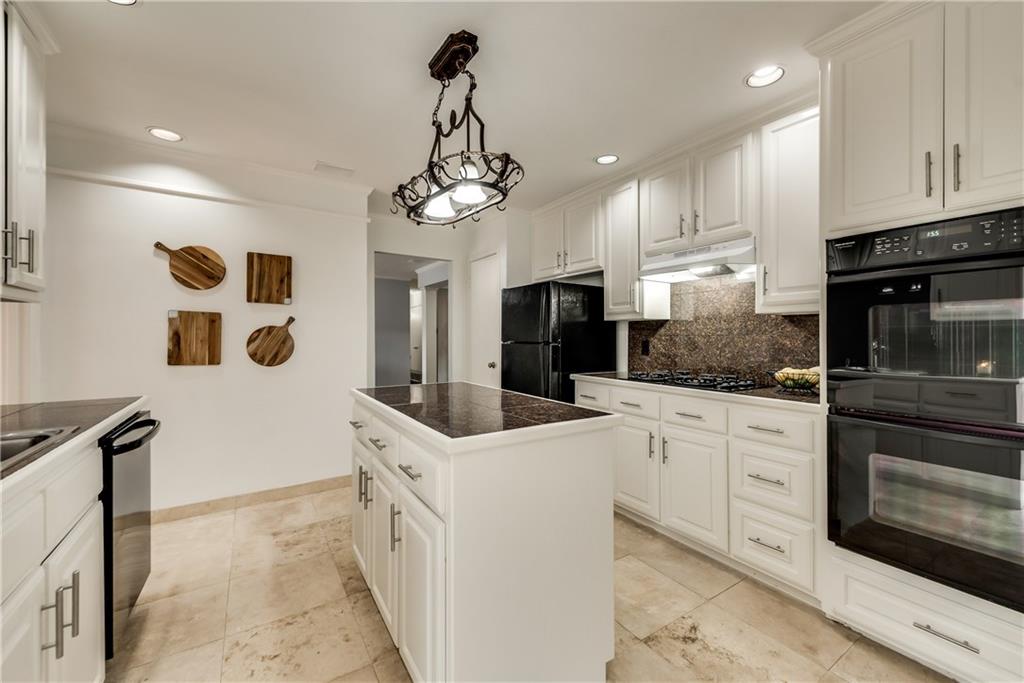 A kitchen with white cabinets , stainless steel appliances , and a large island.