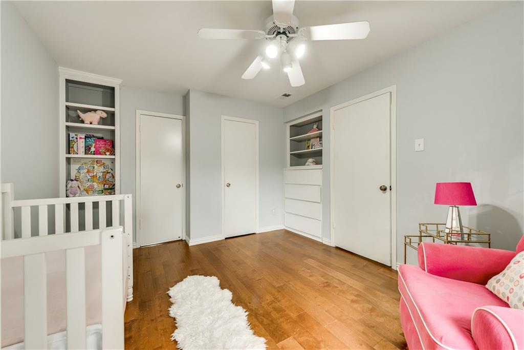 A nursery with a crib , chair , lamp and ceiling fan.