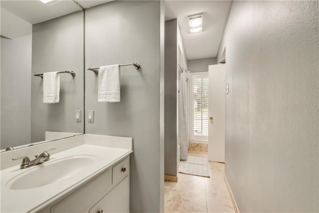 A bathroom with a sink , mirror and towels on the wall.