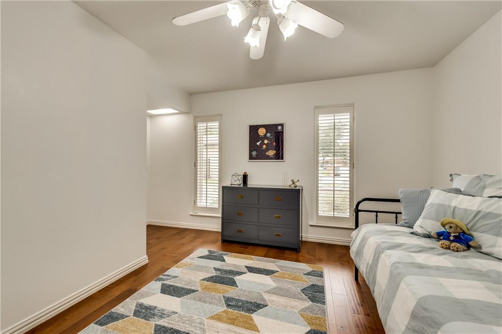 A bedroom with a bed , dresser , rug and ceiling fan.