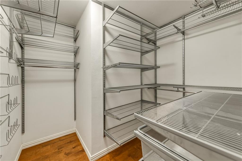 A walk in closet with lots of shelves and a wooden floor.