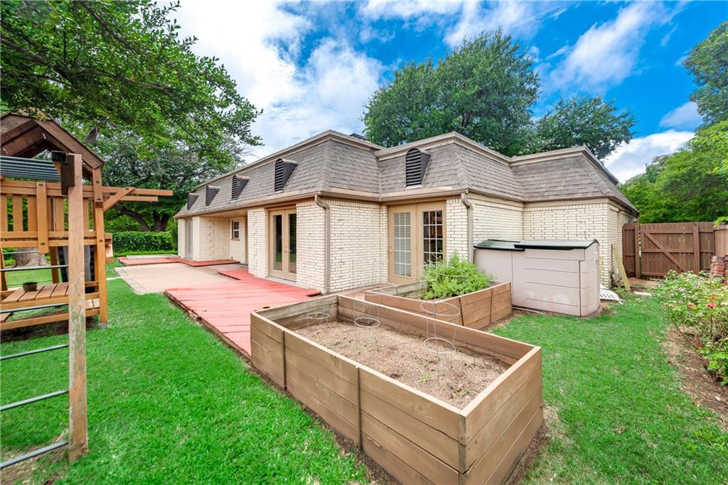 The backyard of a house with wooden planters and a playground.