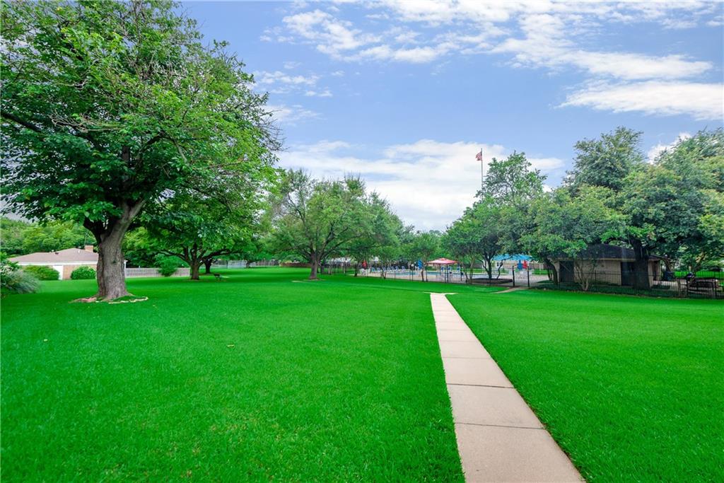 A lush green park with trees and a path going through it.