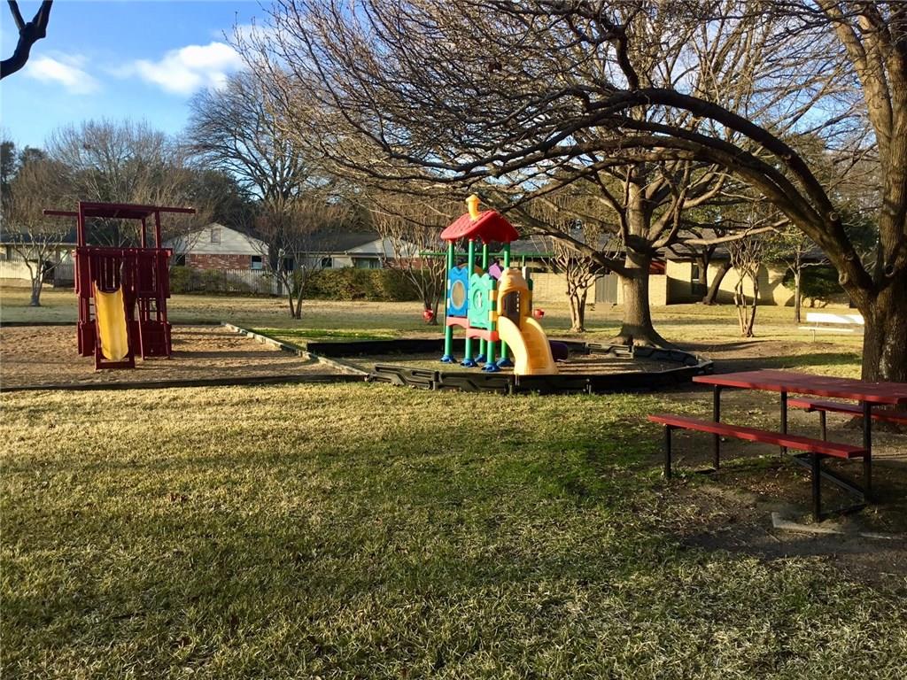 A playground with a slide and a picnic table in a park.