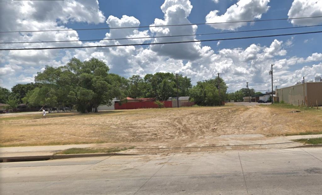 An empty lot with a blue sky and clouds in the background