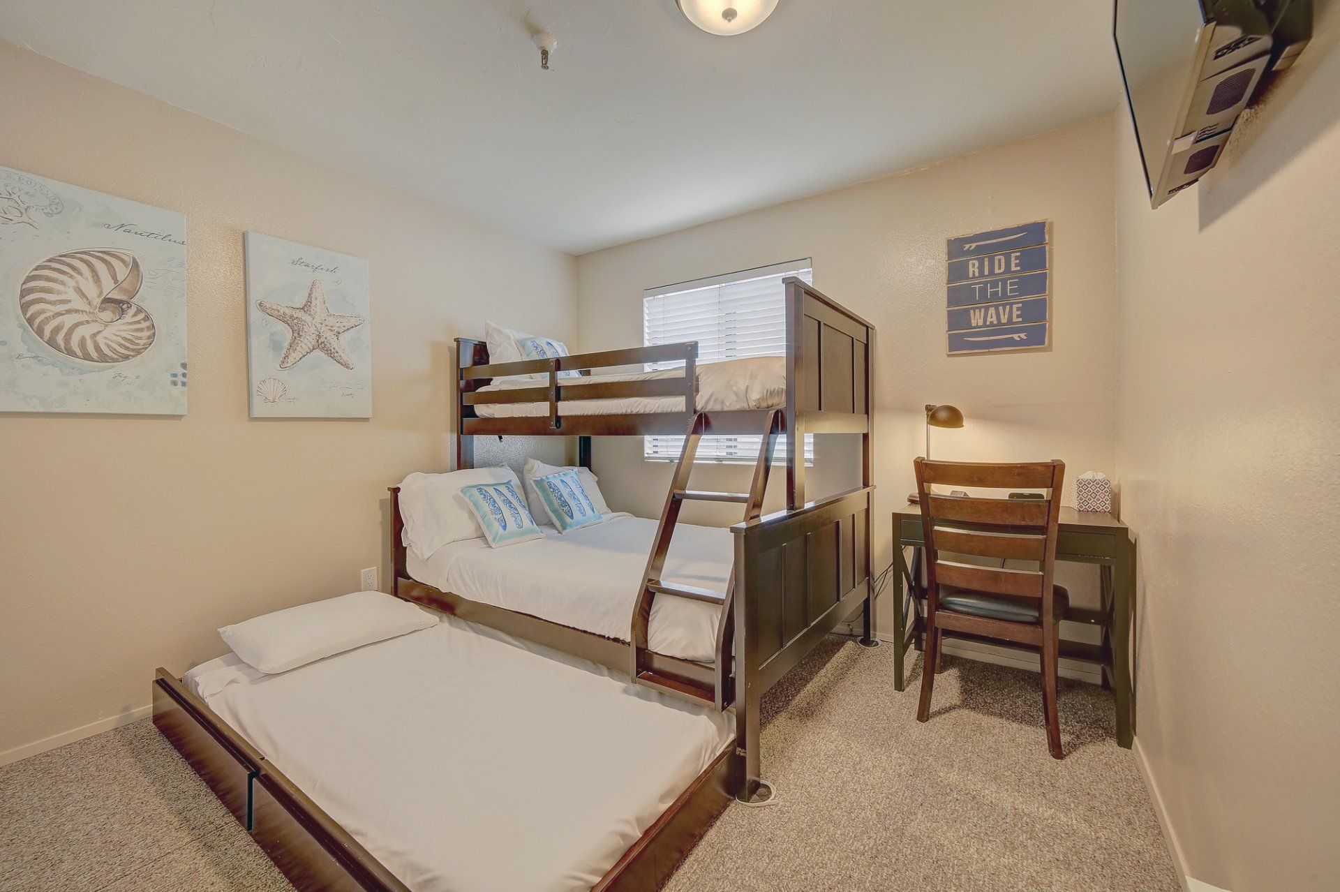 A bedroom with bunk beds , a desk , and a television.