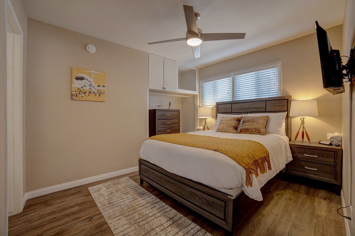 a bedroom with a bed , nightstand , television and ceiling fan .