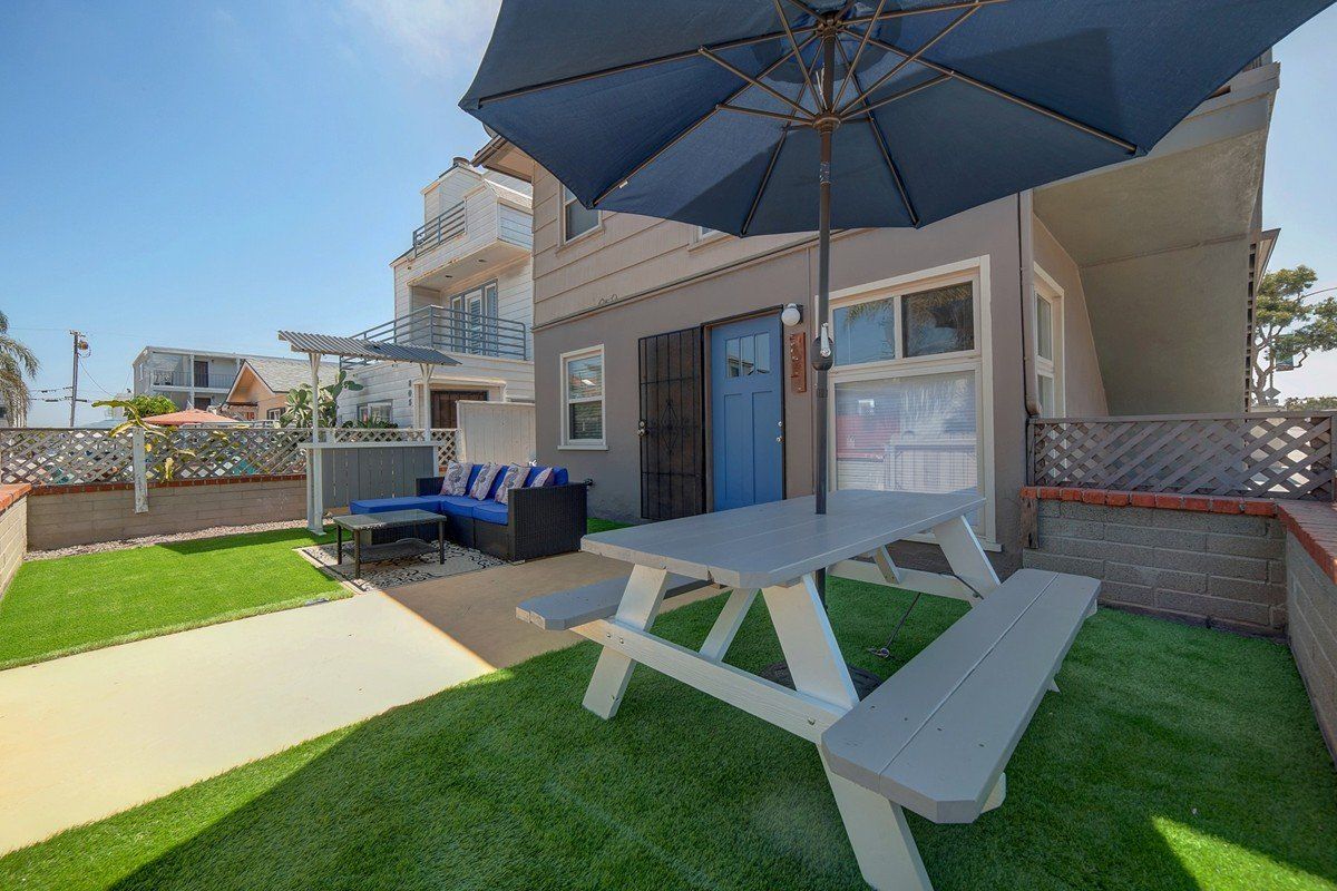 a picnic table with an umbrella in the backyard of a house .