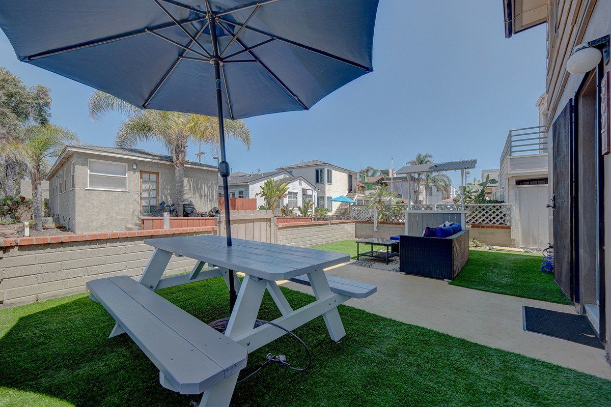 there is a picnic table with an umbrella in the backyard .
