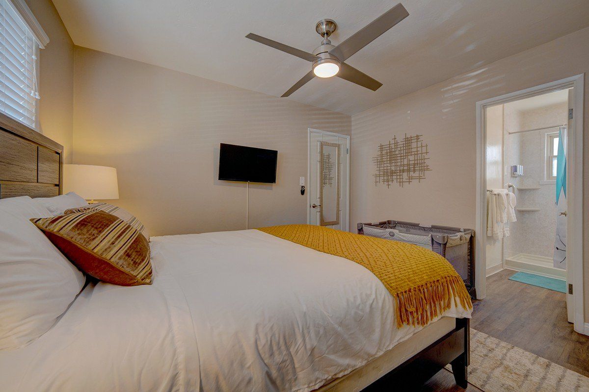 a bedroom with a king size bed , ceiling fan and television .