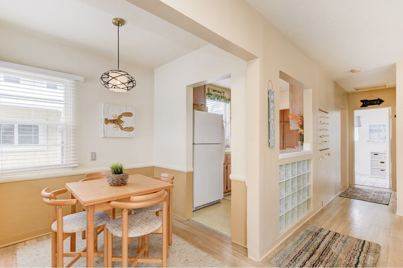 A dining room with a table and chairs and a refrigerator.