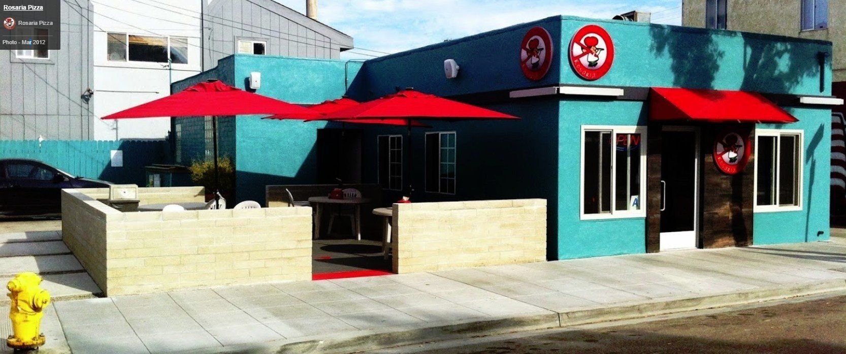 a blue building with red umbrellas in front of it