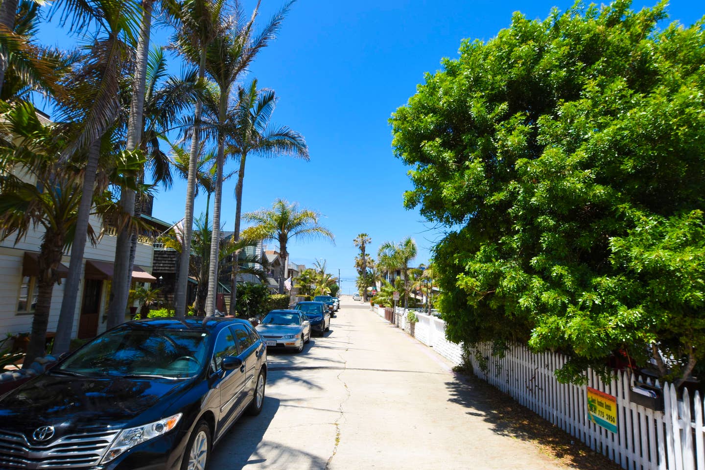 A row of cars are parked on the side of a street.