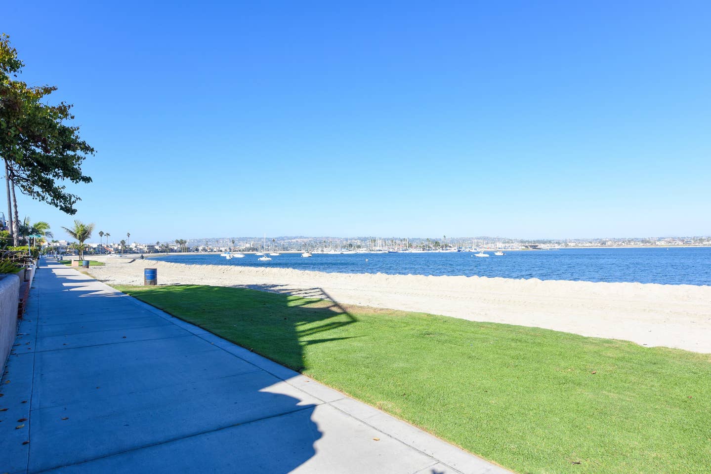 A sidewalk leading to a beach on a sunny day.