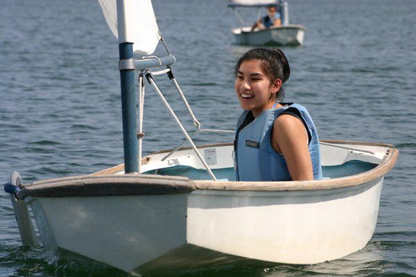 a girl in a life vest is sitting in a small boat