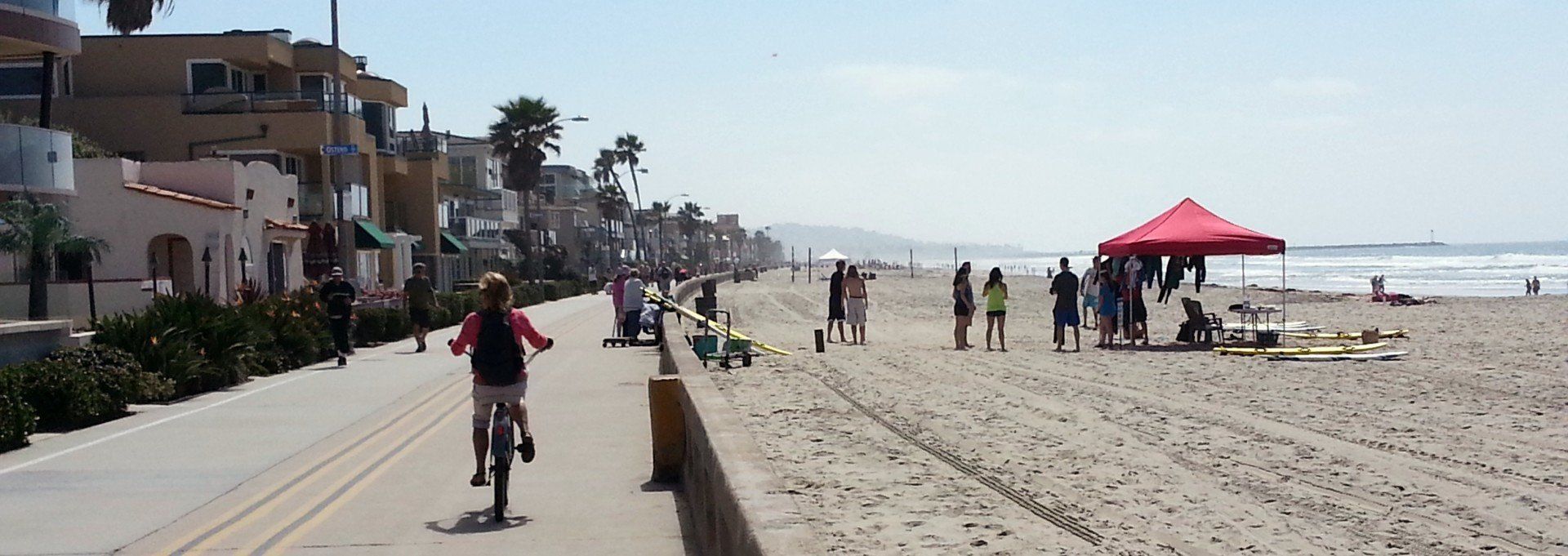 a person is riding a bike on a sidewalk next to a beach .