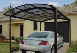 a car is parked under a carport in front of a house .
