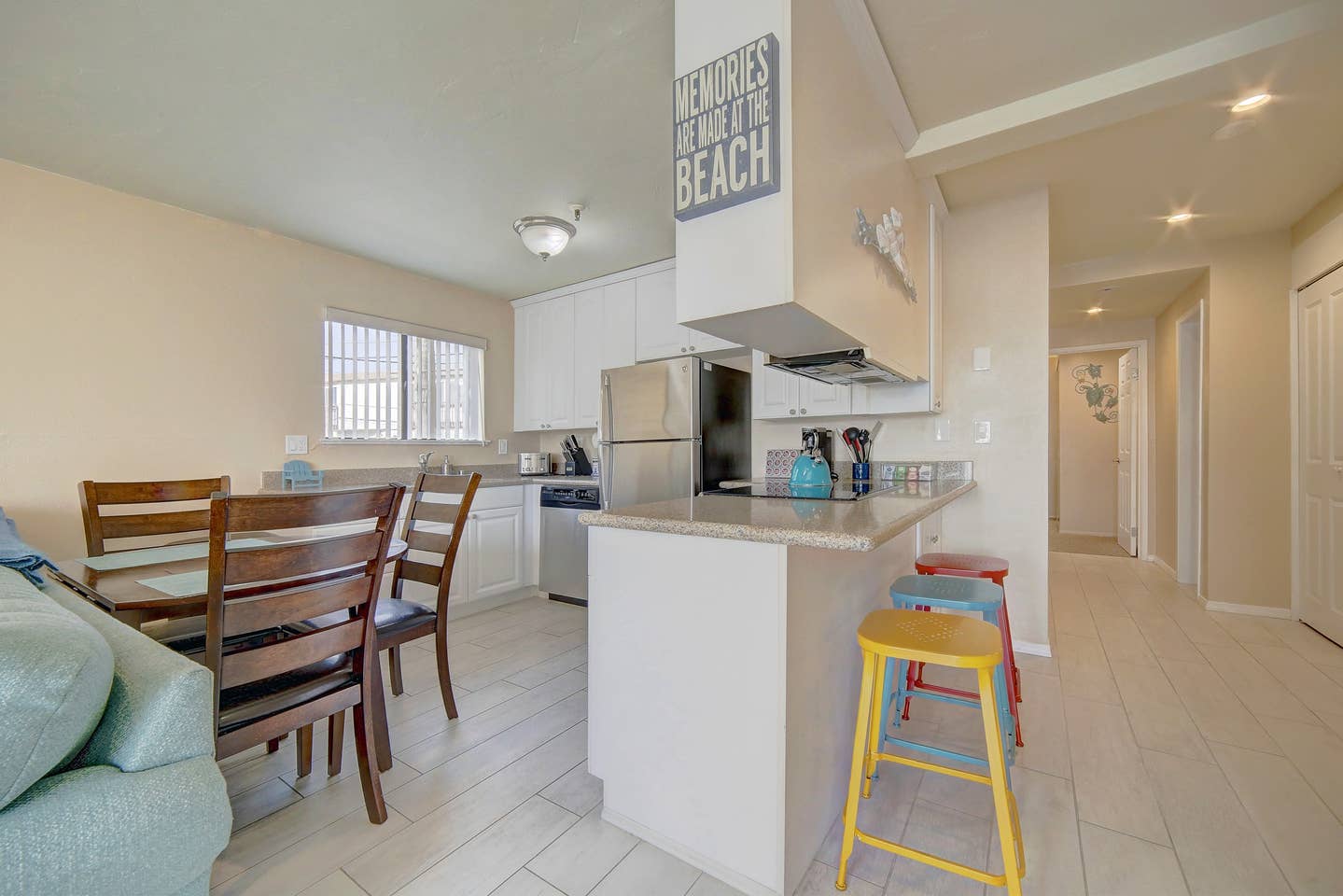 A kitchen and dining room in a house with a sign on the wall that says pearls of the beach.
