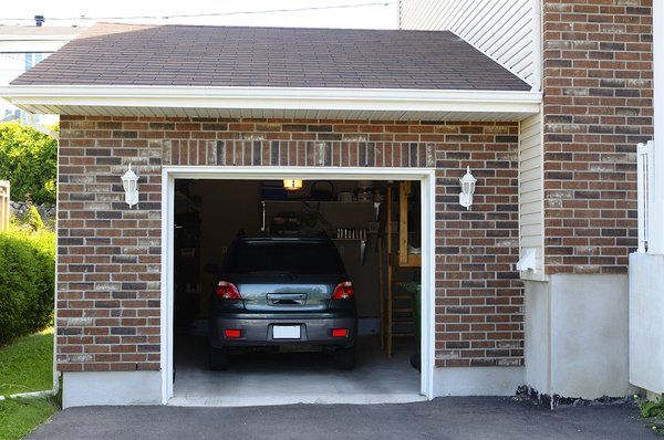 a car is parked in a garage with the door open .