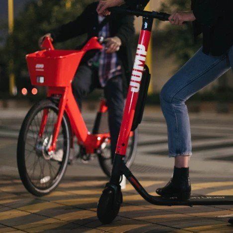 A man is riding a bike next to a jump scooter
