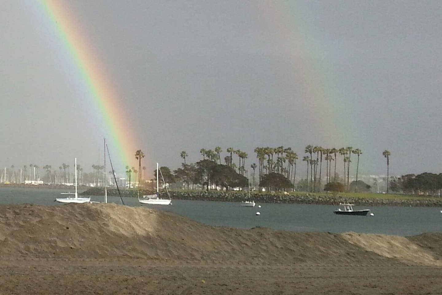 A rainbow over a body of water with boats in it