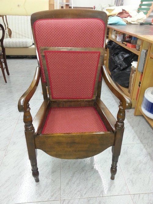 una poltrona in legno rivestita in una stoffa di color rosso