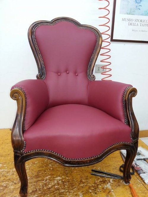 una poltrona in legno rivestita in pelle di color bordeaux