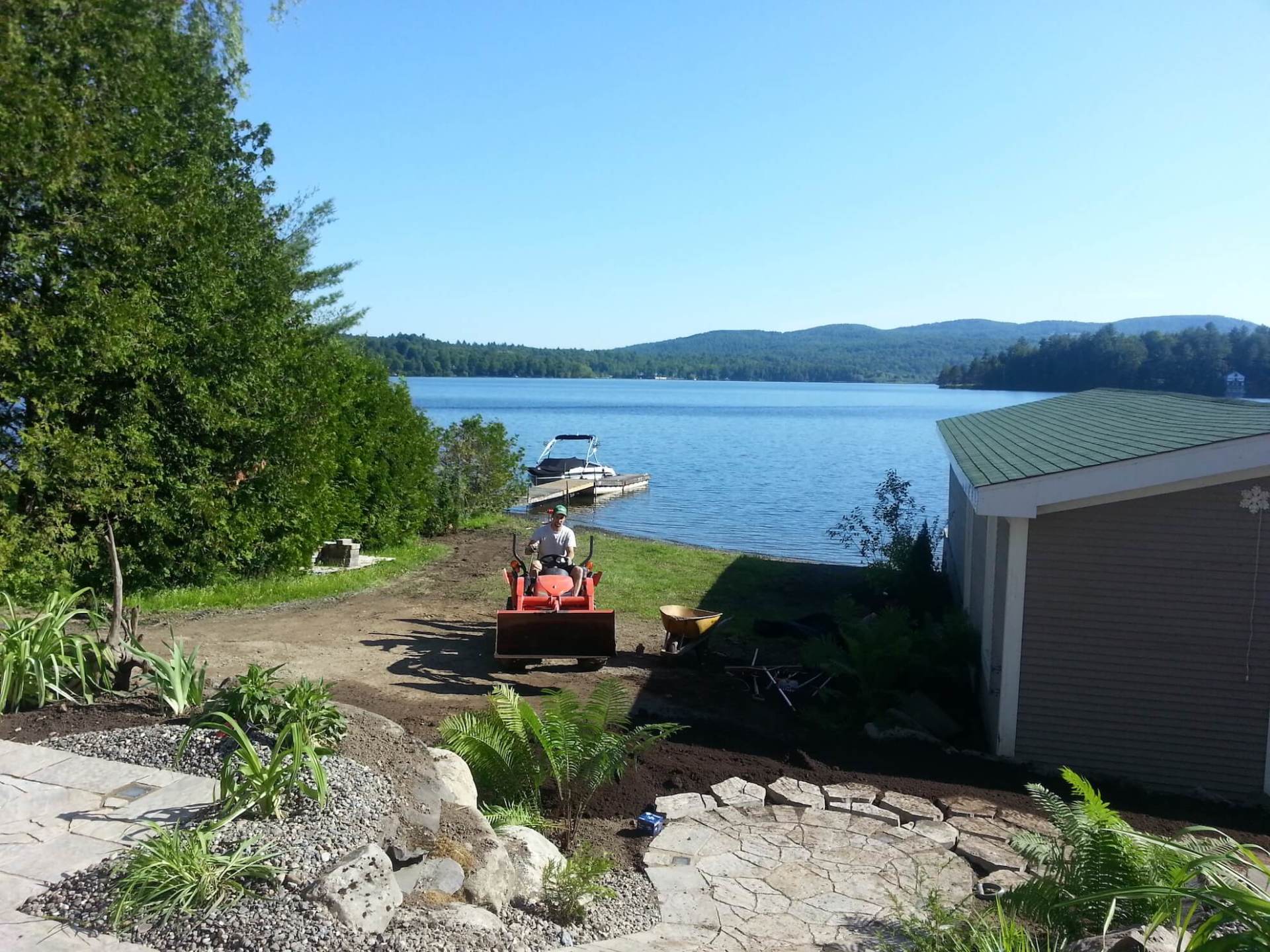 Un homme conduit un bulldozer à côté d'un lac.