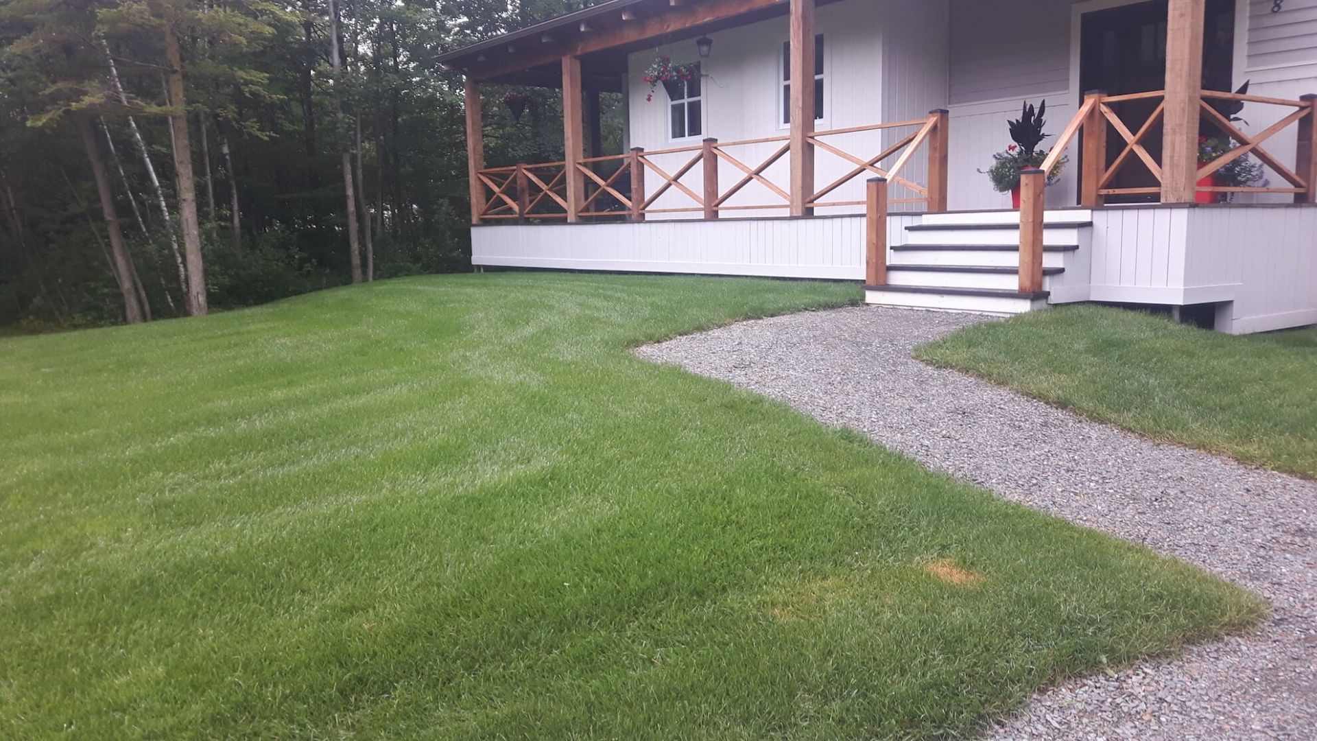 Une maison avec un porche et des escaliers est entourée d'herbe verte luxuriante.