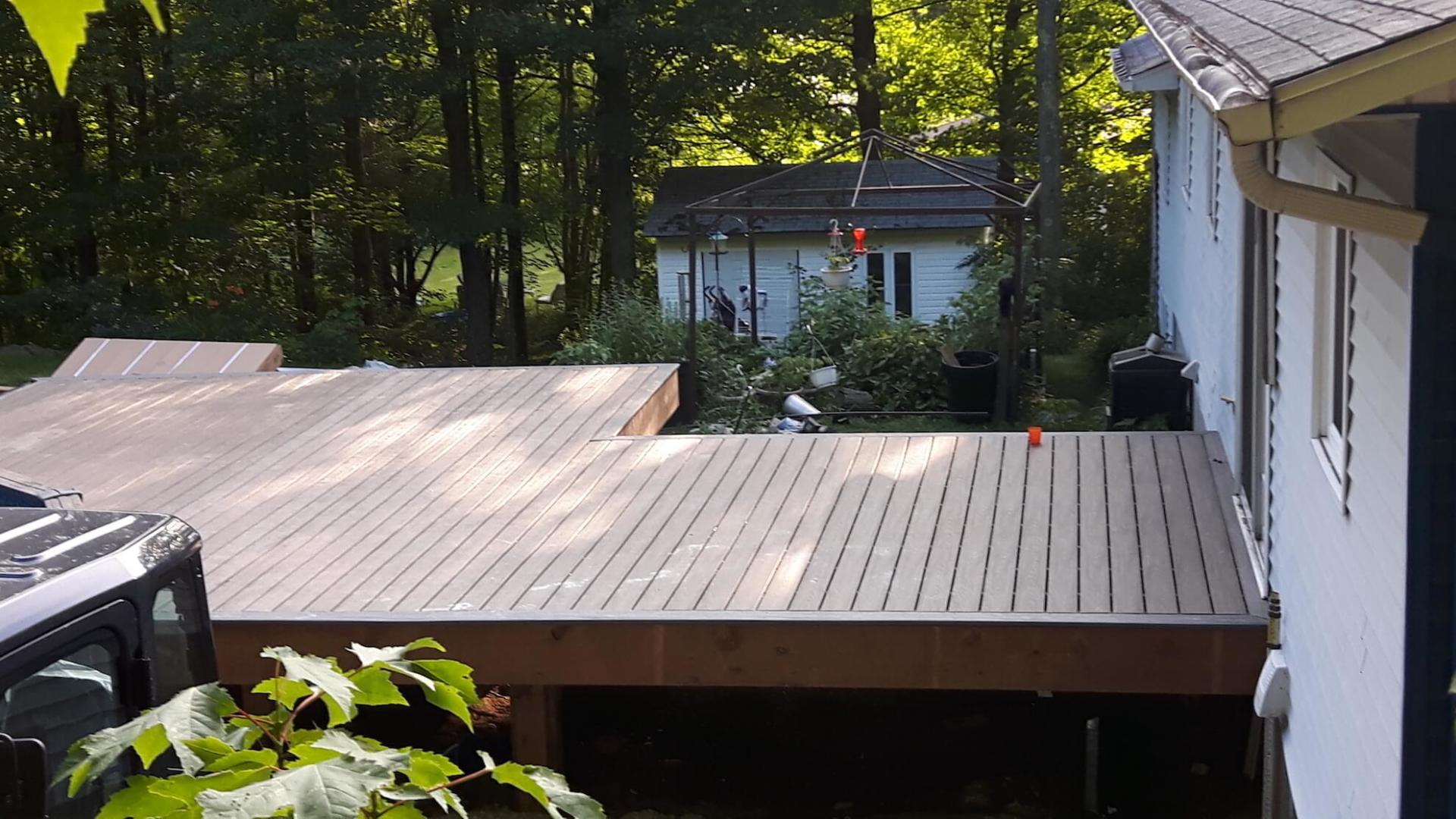 Une maison blanche avec une grande terrasse en bois devant elle