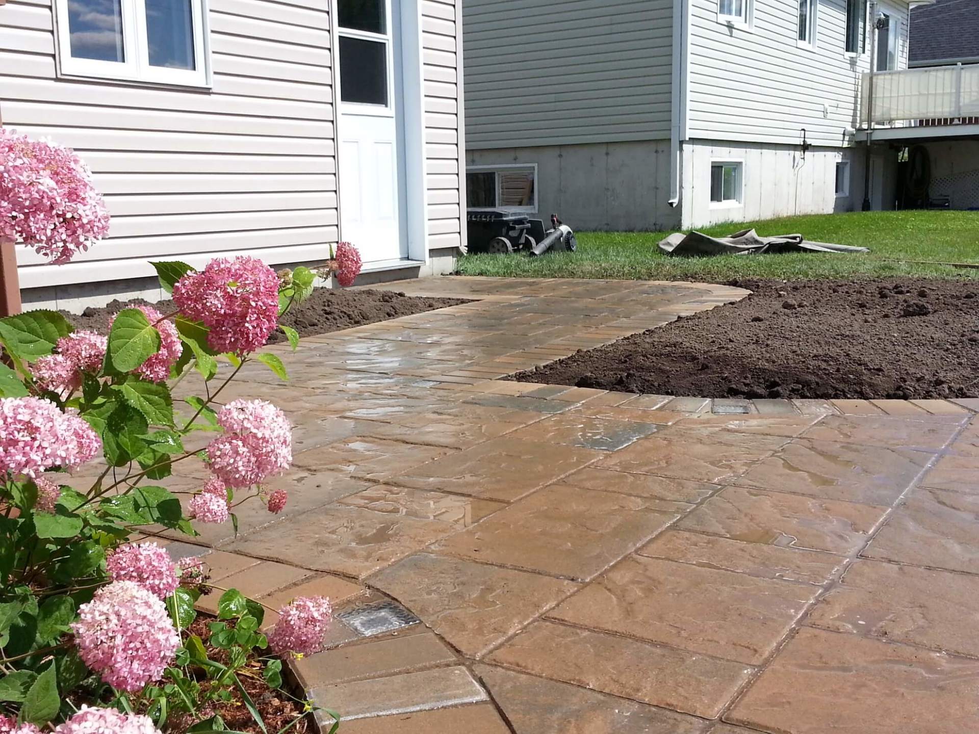 Un patio avec des fleurs roses devant une maison