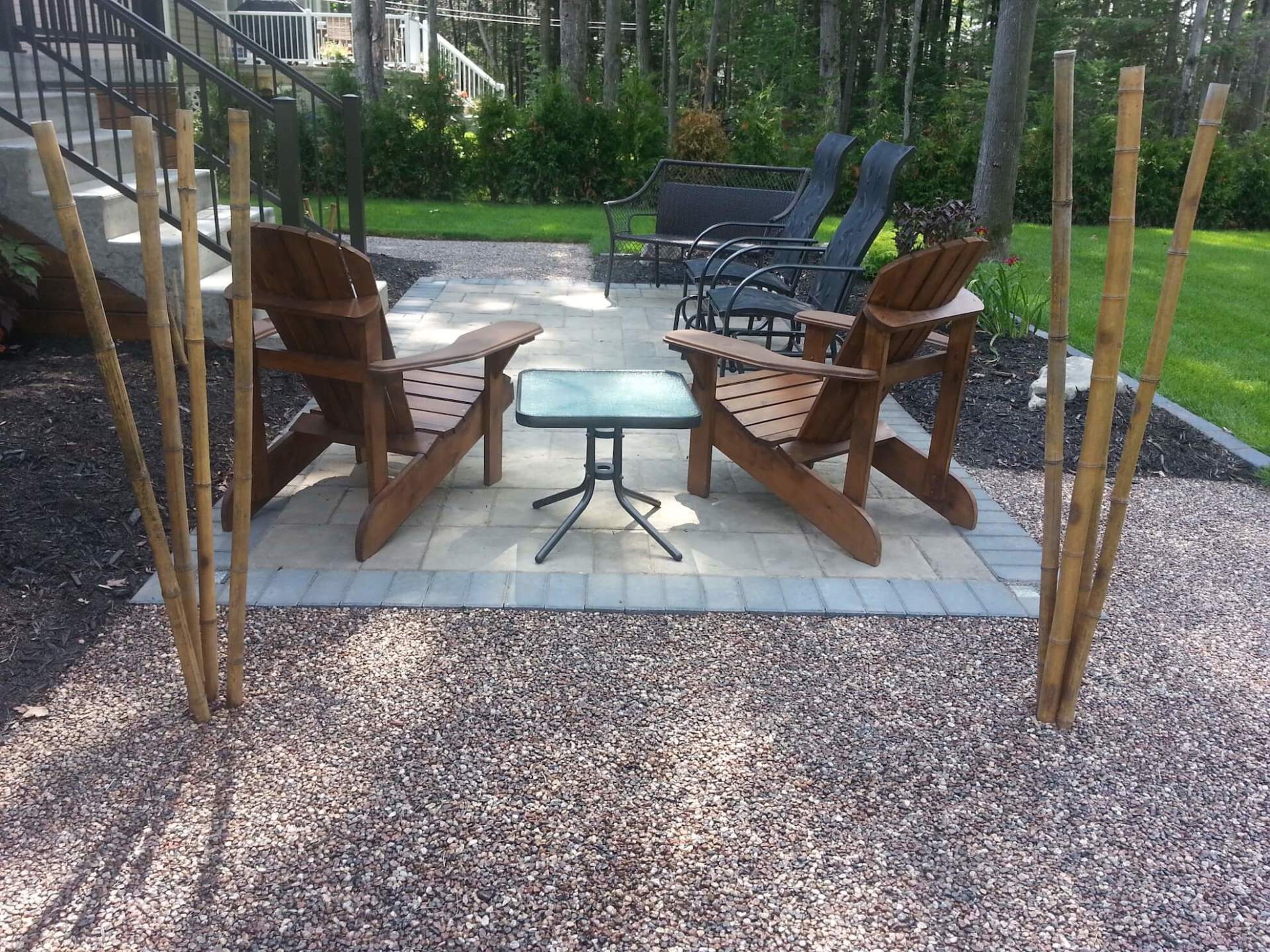 Deux chaises en bois et une table sur une terrasse en gravier
