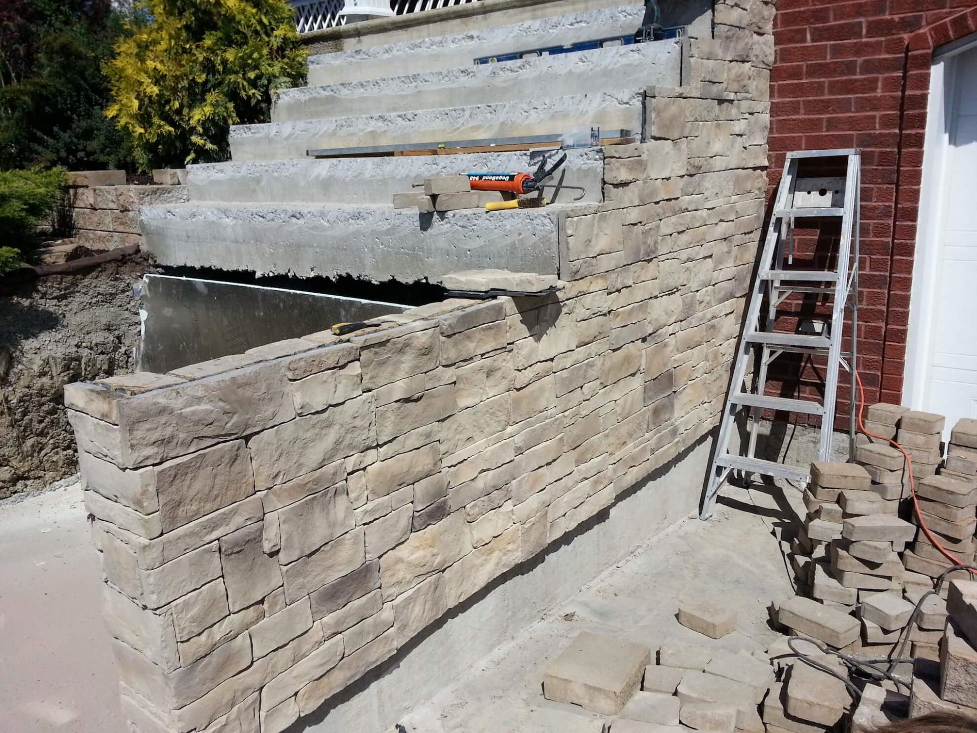 Une échelle est posée à côté d'un mur de briques.