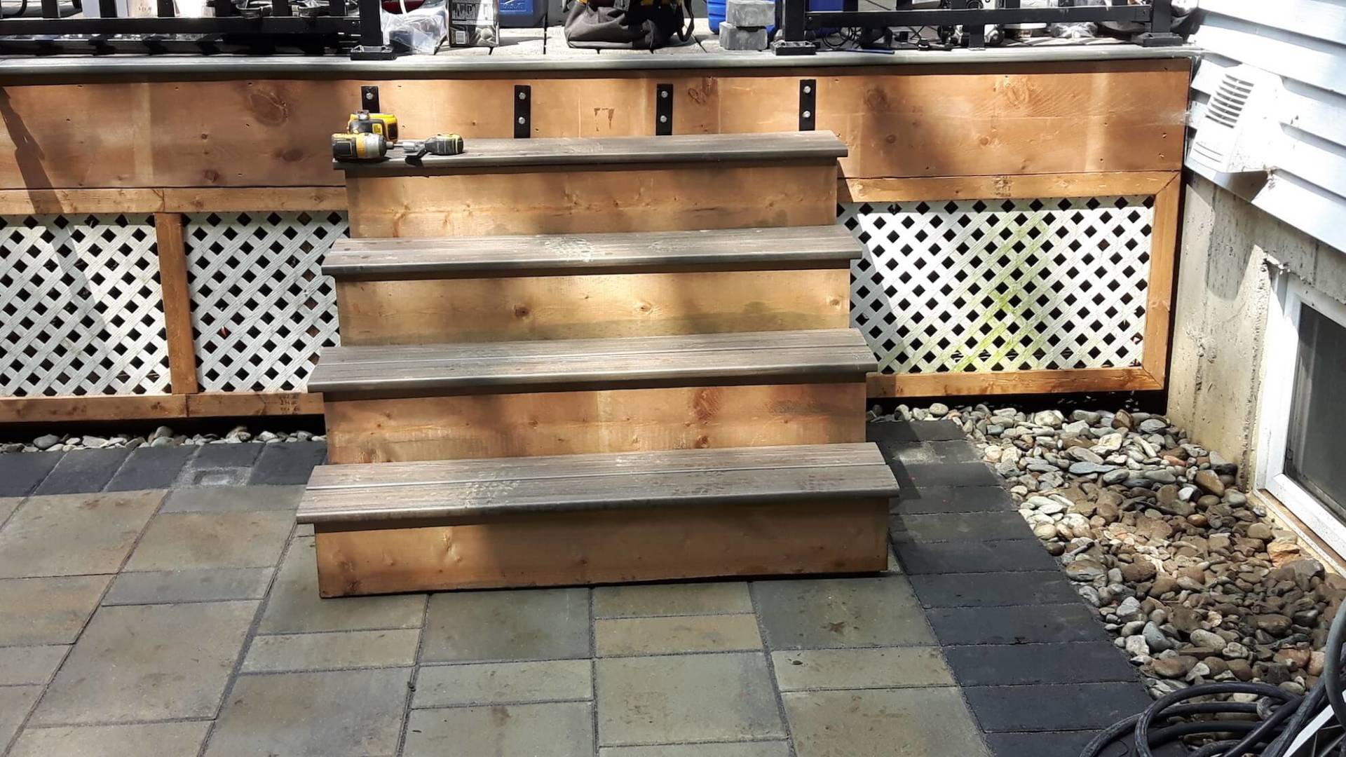 Un escalier en bois se trouve sur un patio à côté d'une maison.