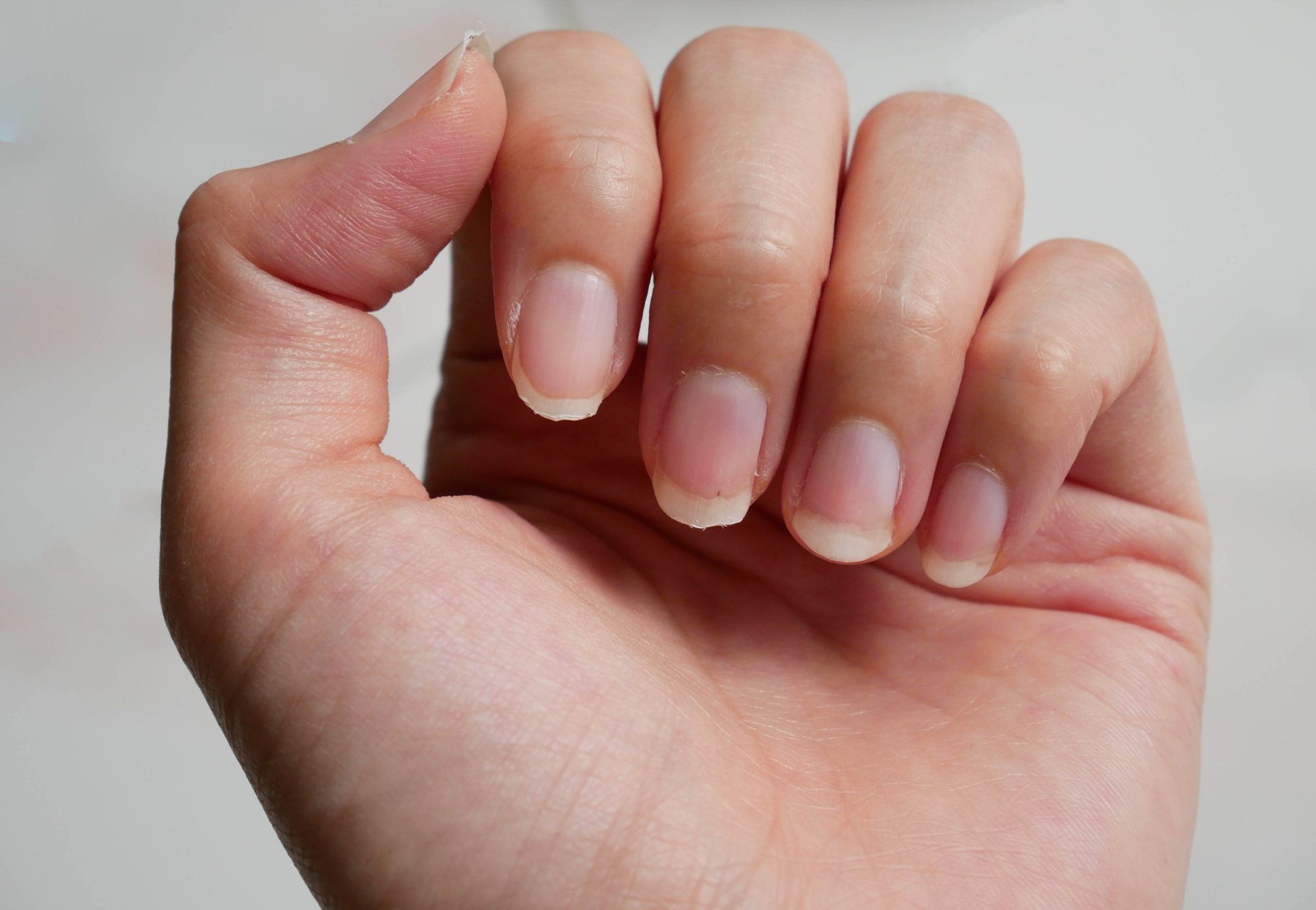 Um close da mão de uma pessoa com unhas compridas.