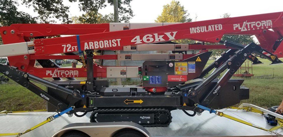 A red and white tree trimming lift on a trailer, labeled