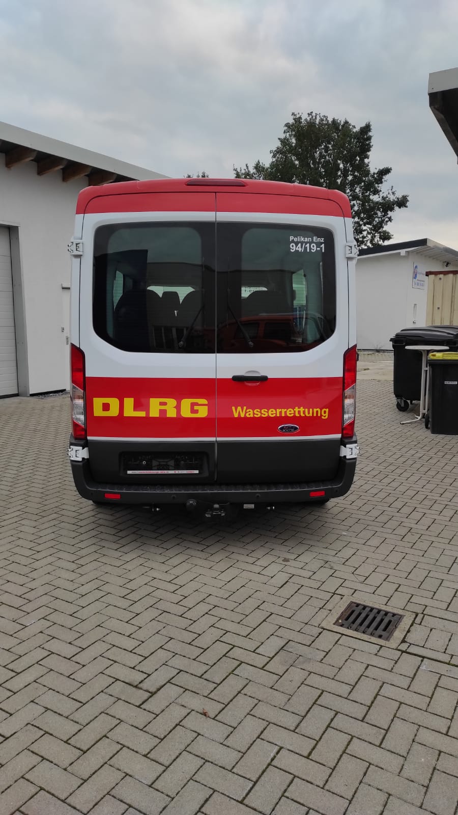 A red and white van with the word dlrg on the back is parked on a brick driveway.