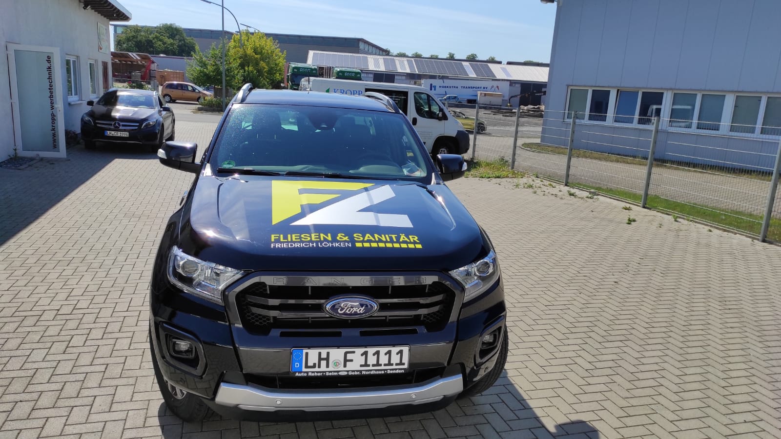 A ford ranger is parked in a parking lot in front of a building.