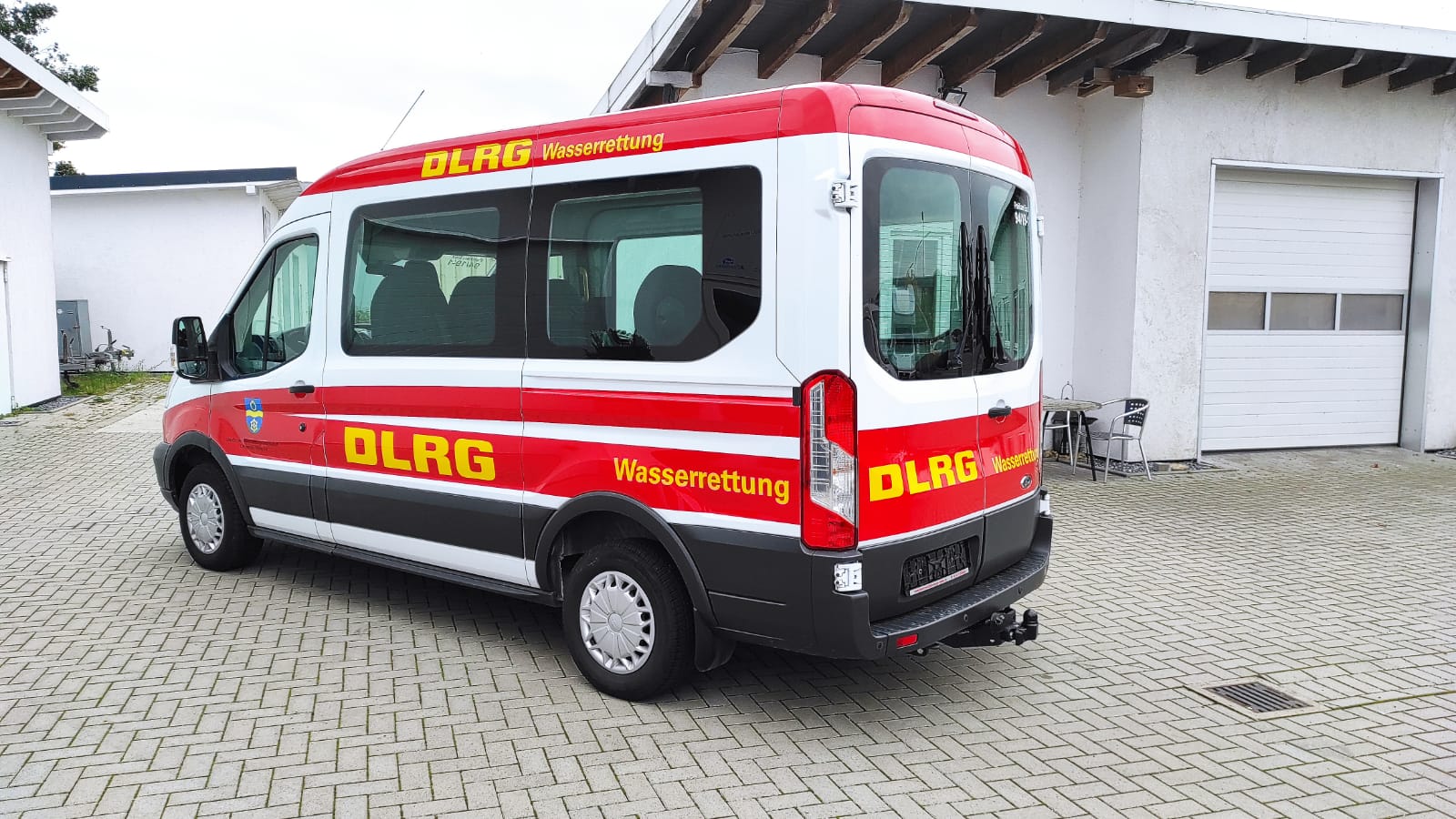 A red and white van is parked in front of a building.
