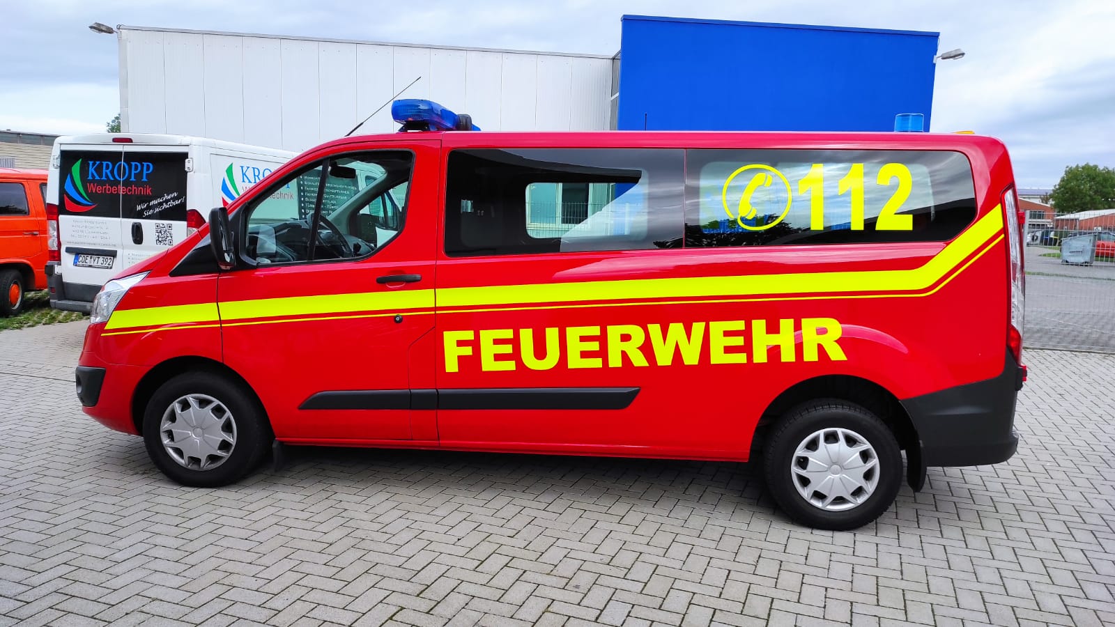 A red feuerwehr van is parked in front of a building.