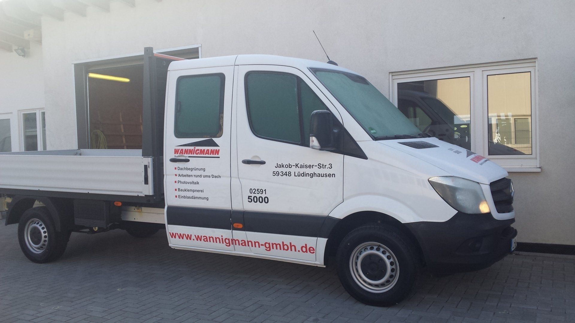 A white van is parked in front of a building