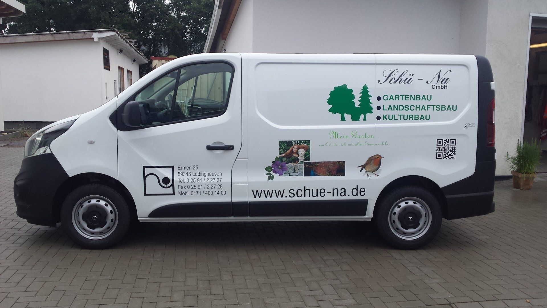 A white van is parked in front of a building