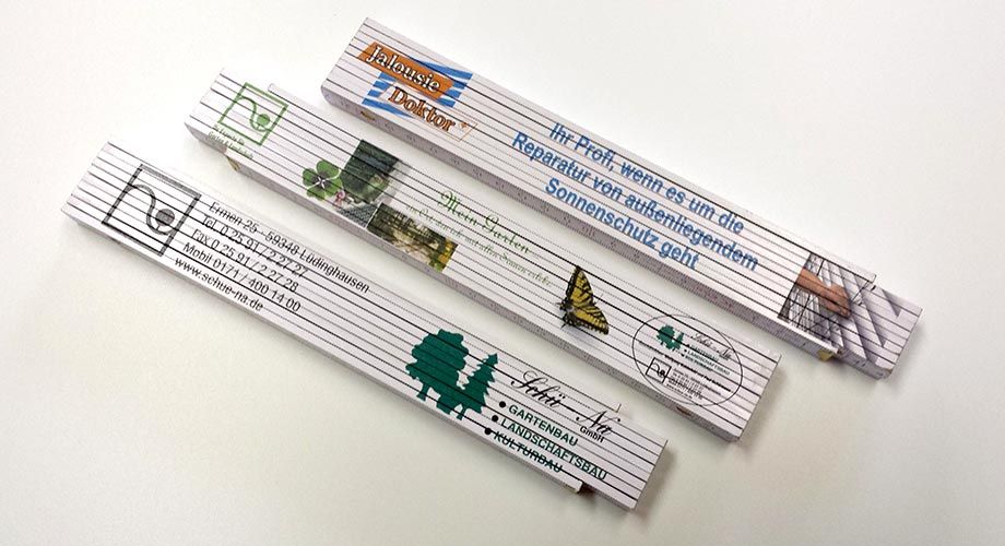 Three folding ruler with different designs on them are sitting on a table.