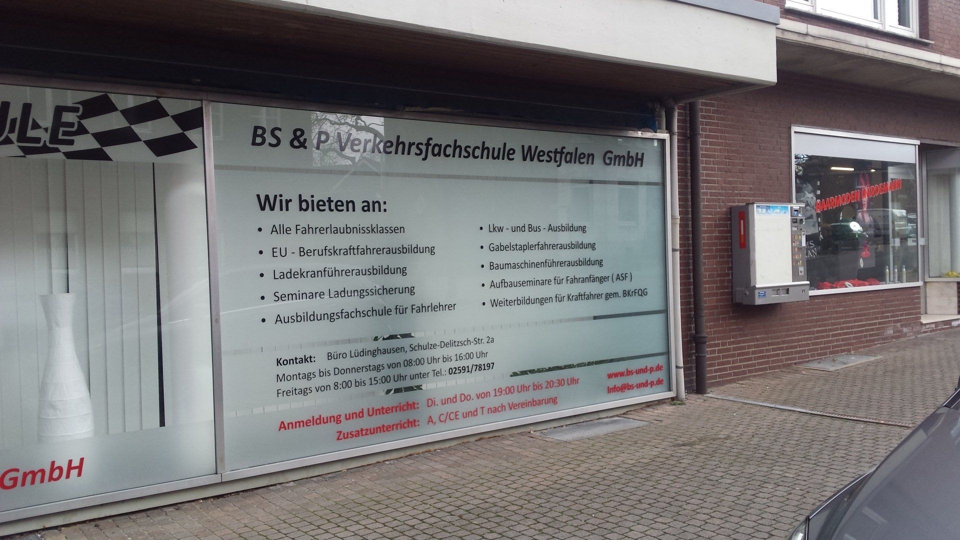A car is parked in front of a building with a sign on the window.