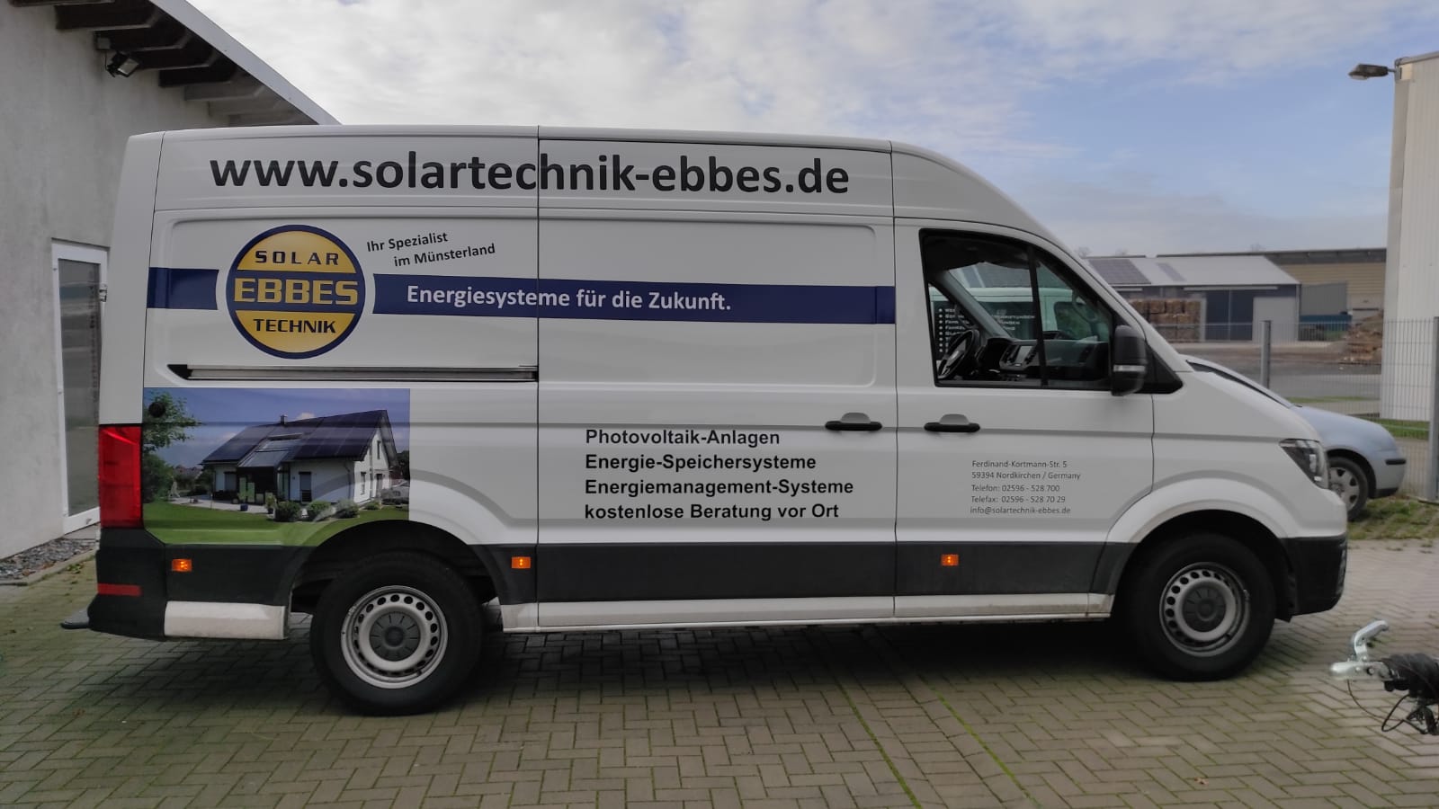 A white van is parked in front of a building.